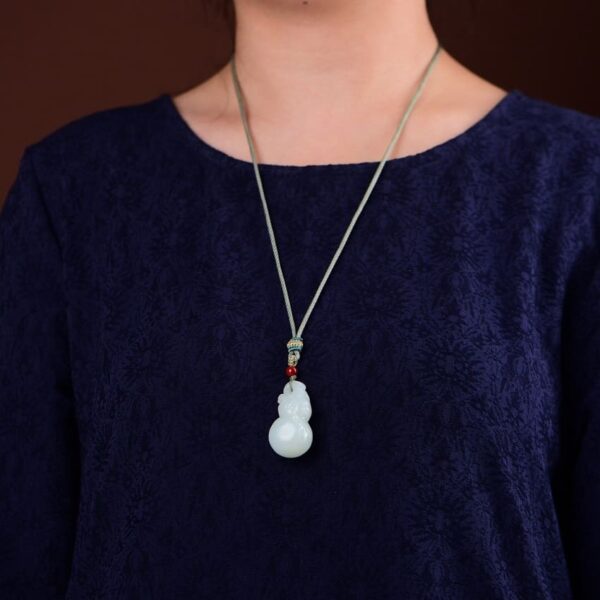 Model wearing elegant Hetian Jade Fu Lu Shou Gourd pendant, highlighting its auspicious design and rich color.